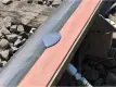 A close-up view of a railroad track where a puddle of purple-grey liquid is shown on an orange foam bar attached to the rail