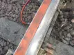 A close-up view of a railroad track where a puddle of clear liquid is shown on an orange foam bar attached to the rail